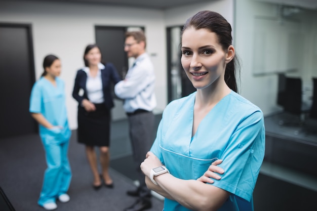 Uśmiechnięta pielęgniarka stojąca z rękami skrzyżowanymi