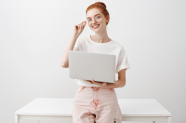 Uśmiechnięta ruda dziewczyna za pomocą laptopa i patrzeć