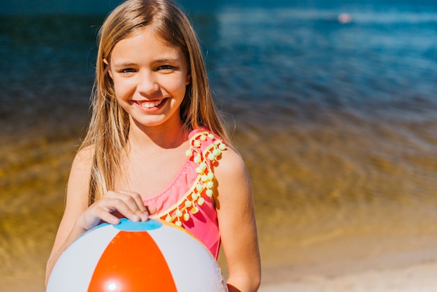 Bezpłatne zdjęcie uśmiechnięta śliczna dziewczyna z plażową piłką