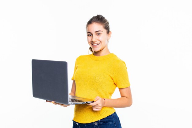 Uśmiechnięta śliczna nastoletnia dziewczyna używa laptop nad biel ścianą
