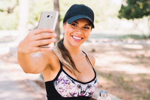 Uśmiechnięta sprawności fizycznej młoda kobieta bierze selfie od telefonu komórkowego