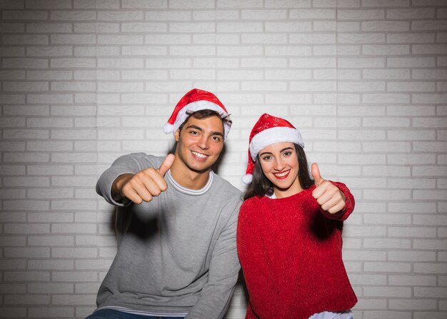 Uśmiechnięta świąteczna para pokazuje aprobaty