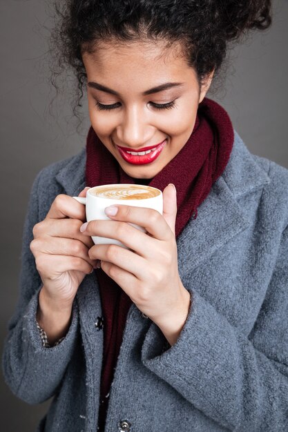 Uśmiechnięta szczęśliwa kobieta trzyma filiżankę kawy w żakiecie