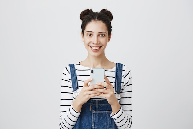 Uśmiechnięta szczęśliwa nastoletnia kobieta z smartphone