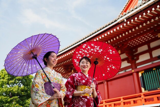 Uśmiechnięte kobiety o niskim kącie trzymają parasol wagasa