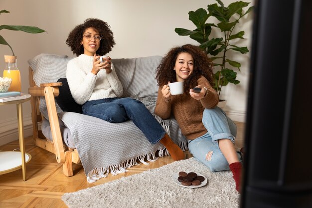Uśmiechnięte kobiety oglądające telewizję w pełnym ujęciu
