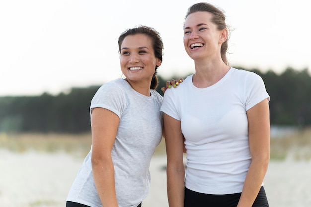 Uśmiechnięte kobiety pozują razem podczas ćwiczeń na plaży