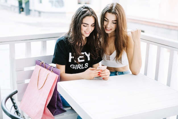 Uśmiechnięte kobiety używa smartphone w kawiarni