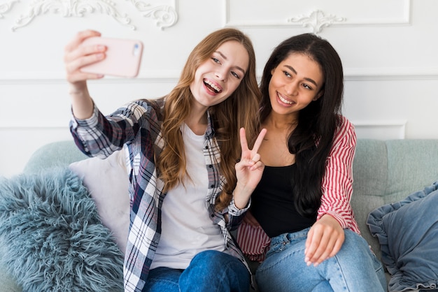 Bezpłatne zdjęcie uśmiechnięte młode kobiety bierze selfie na telefonie