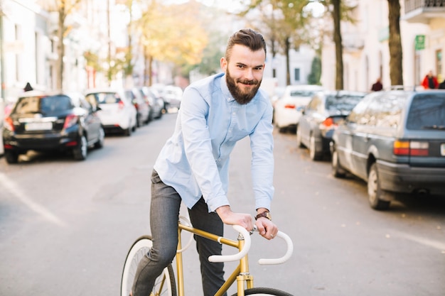 Uśmiechniętego mężczyzna jeździecki bicykl wzdłuż drogi