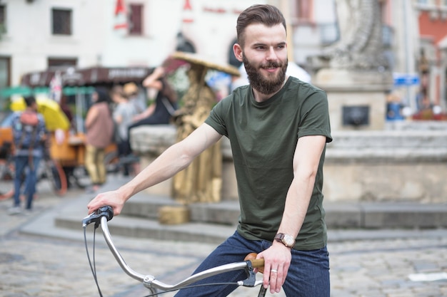 Uśmiechniętego młodego człowieka jeździecki bicykl w mieście
