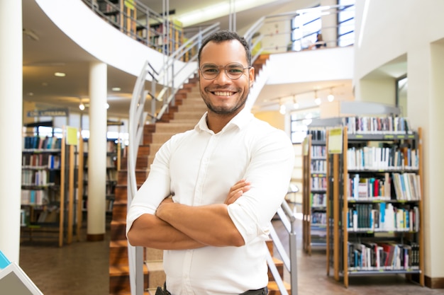 Uśmiechnięty amerykanina afrykańskiego pochodzenia mężczyzna pozuje przy biblioteką publiczną