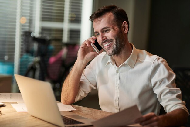 Uśmiechnięty biznesmen rozmawia przez telefon komórkowy