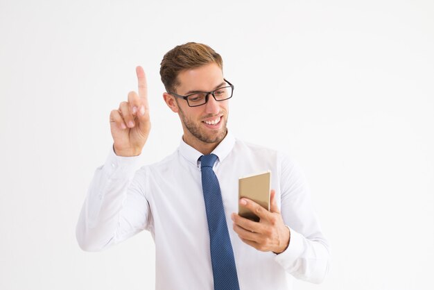 Uśmiechnięty biznesowy mężczyzna używa smartphone i podnoszący palec up