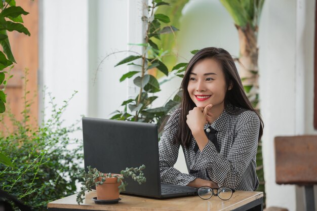 Uśmiechnięty bizneswoman pracuje na laptopie w kawiarni