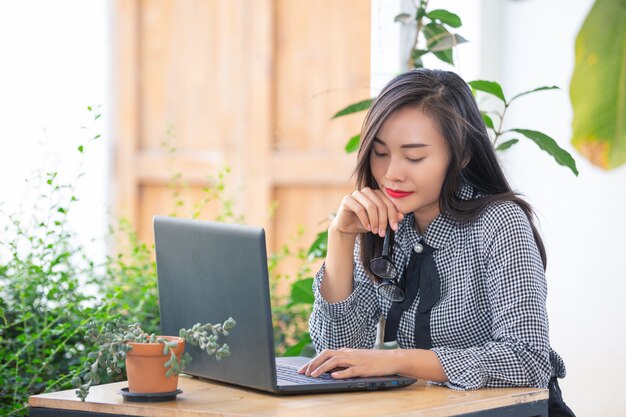 Uśmiechnięty bizneswoman pracuje na laptopie w kawiarni