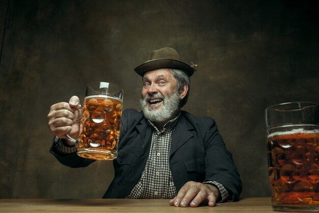 Uśmiechnięty brodaty mężczyzna pije piwo w pubie