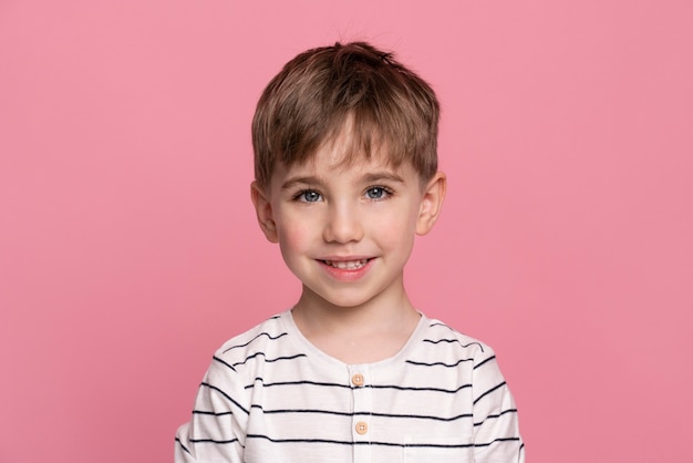 Bezpłatne zdjęcie uśmiechnięty chłopiec na różowym tle