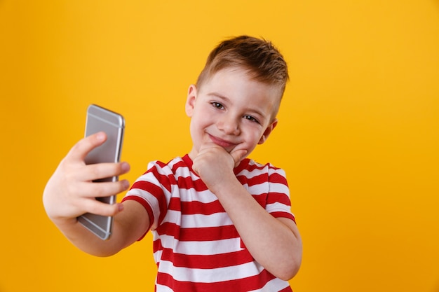 Uśmiechnięty chłopiec robi selfie i myśleć o czymś