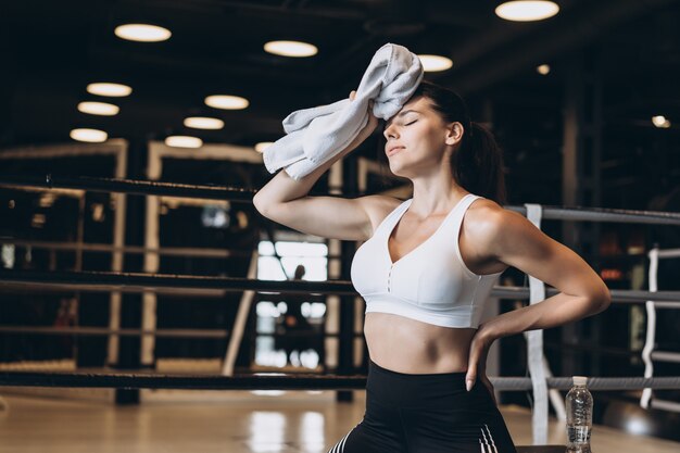 Uśmiechnięty dysponowany dziewczyny mienia ręcznik i brać odpoczynek w gym. Dziewczyna ociera pot ręcznikiem