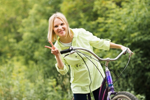 Uśmiechnięty kobiety mienia pokoju znak na bicyklu