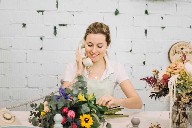 Bezpłatne zdjęcie uśmiechnięty kwiaciarni mówienie na telefonie