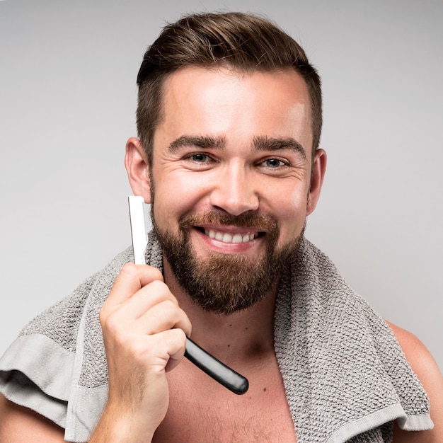 Uśmiechnięty mężczyzna goli brodę