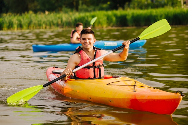 Bezpłatne zdjęcie uśmiechnięty mężczyzna paddling kajak na jeziorze