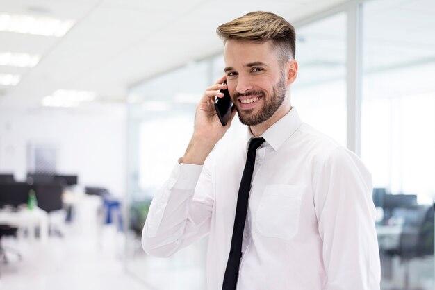 Uśmiechnięty mężczyzna rozmawia przez telefon komórkowy