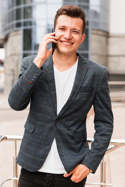 Uśmiechnięty mężczyzna rozmawia przez telefon w drodze do pracy