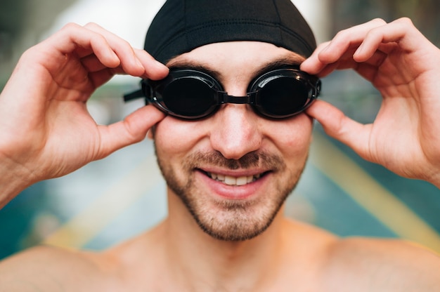 Uśmiechnięty mężczyzna układający okulary pływackie