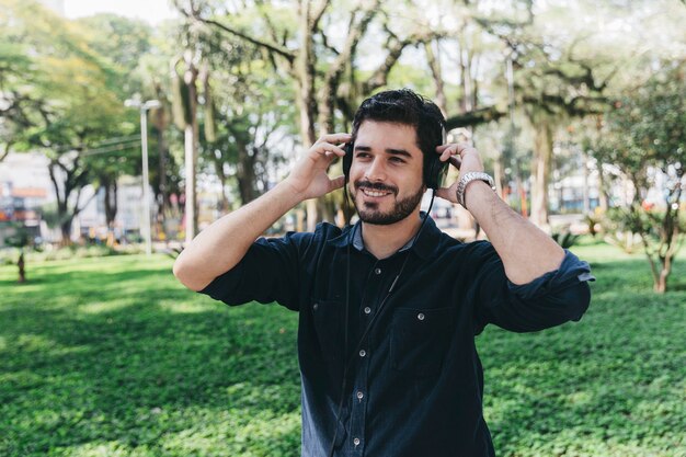 Uśmiechnięty mężczyzna w słuchawkach pozuje w parku