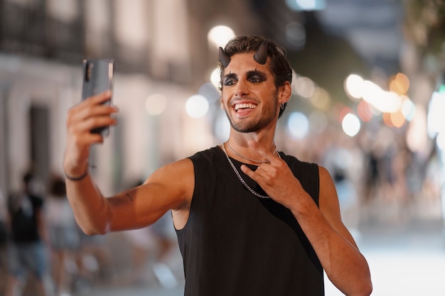 Bezpłatne zdjęcie uśmiechnięty mężczyzna z rogami robi selfie widok z przodu
