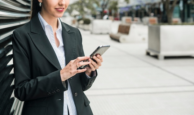 Uśmiechnięty młody bizneswoman używa mądrze telefon