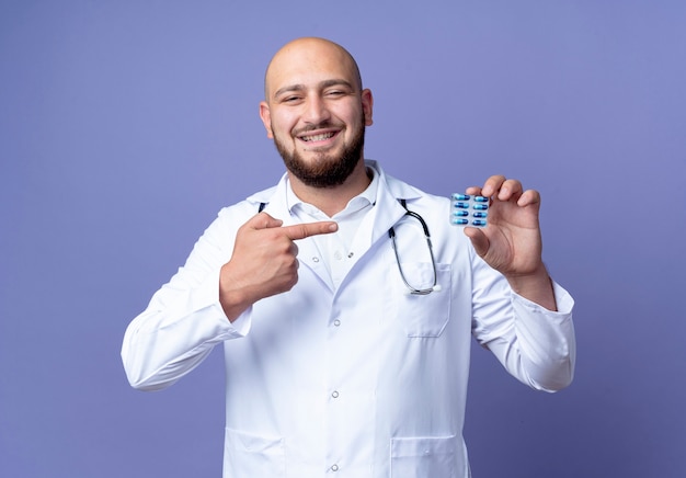 Uśmiechnięty młody łysy mężczyzna lekarz ubrany w szlafrok i stetoskop