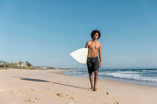 Uśmiechnięty młody męski surfingowiec patrzeje kamerę