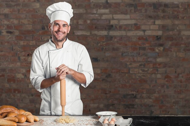 Uśmiechnięty piec chleb z ciastem i składnikami na kuchennym worktop