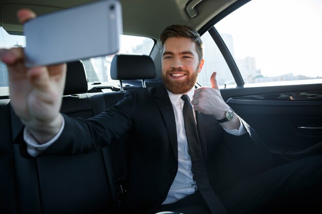 Uśmiechnięty pomyślny biznesowy mężczyzna bierze selfie