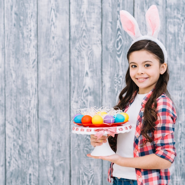 Uśmiechnięty Portret Dziewczyna Trzyma Easter Jajka Na Cakestand Patrzeje Kamera