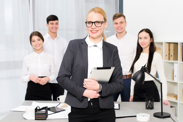 Bezpłatne zdjęcie uśmiechnięty portret młody bizneswoman trzyma cyfrową pastylkę w ręki pozyci przed jej kolegą