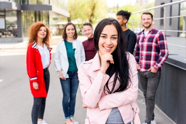 Uśmiechnięty portret pięknej kobiety stojącej przed jej przyjaciółmi