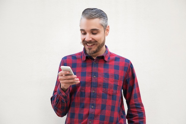 Uśmiechnięty przystojny mężczyzna używa smartphone