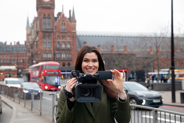 Uśmiechnięty reporter trzymający aparat w średnim ujęciu