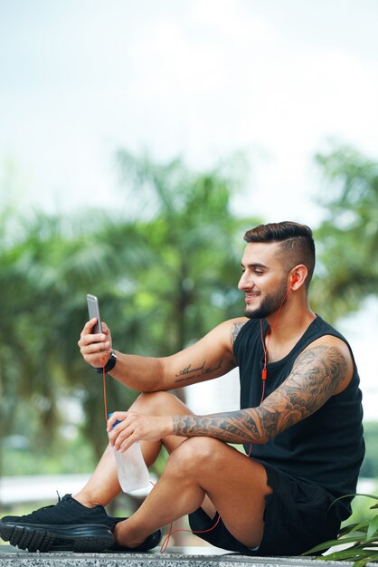 Uśmiechnięty sportowiec używa telefon outdoors