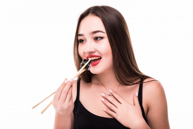 Uśmiechnięty zdziwiony azjatykci kobieta smaku suszi rolki ubierał w czarnych czerwonych wargach odizolowywać