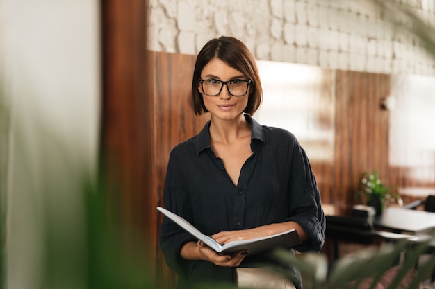 Uśmiechnięty Żeński kierownik w eyeglasses z dokumentami w rękach