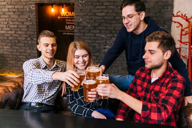 Uśmiechnięty znajomych siedzi razem opiekania szklanki piwa