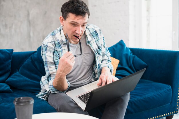 Uważny mężczyzna patrząc na laptopa w domu