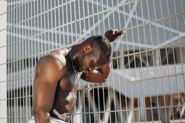Uwodzicielski African American człowiek z muscels pozuje z nagich piersi przed ogrodzeniem