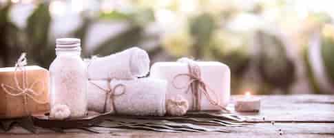 Bezpłatne zdjęcie uzdrowiskowe mydło ręcznie robione z białymi ręcznikami i solą morską, kompozycja tropikalnych liści ze świecą, tło drewniane